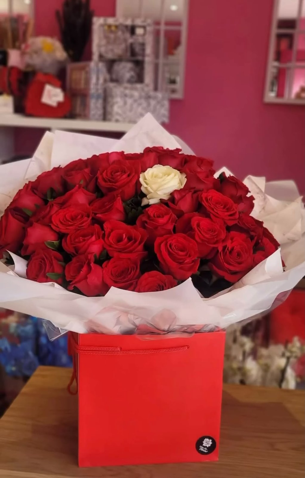 Popular bouquet of red roses with one white rose, set in a red box