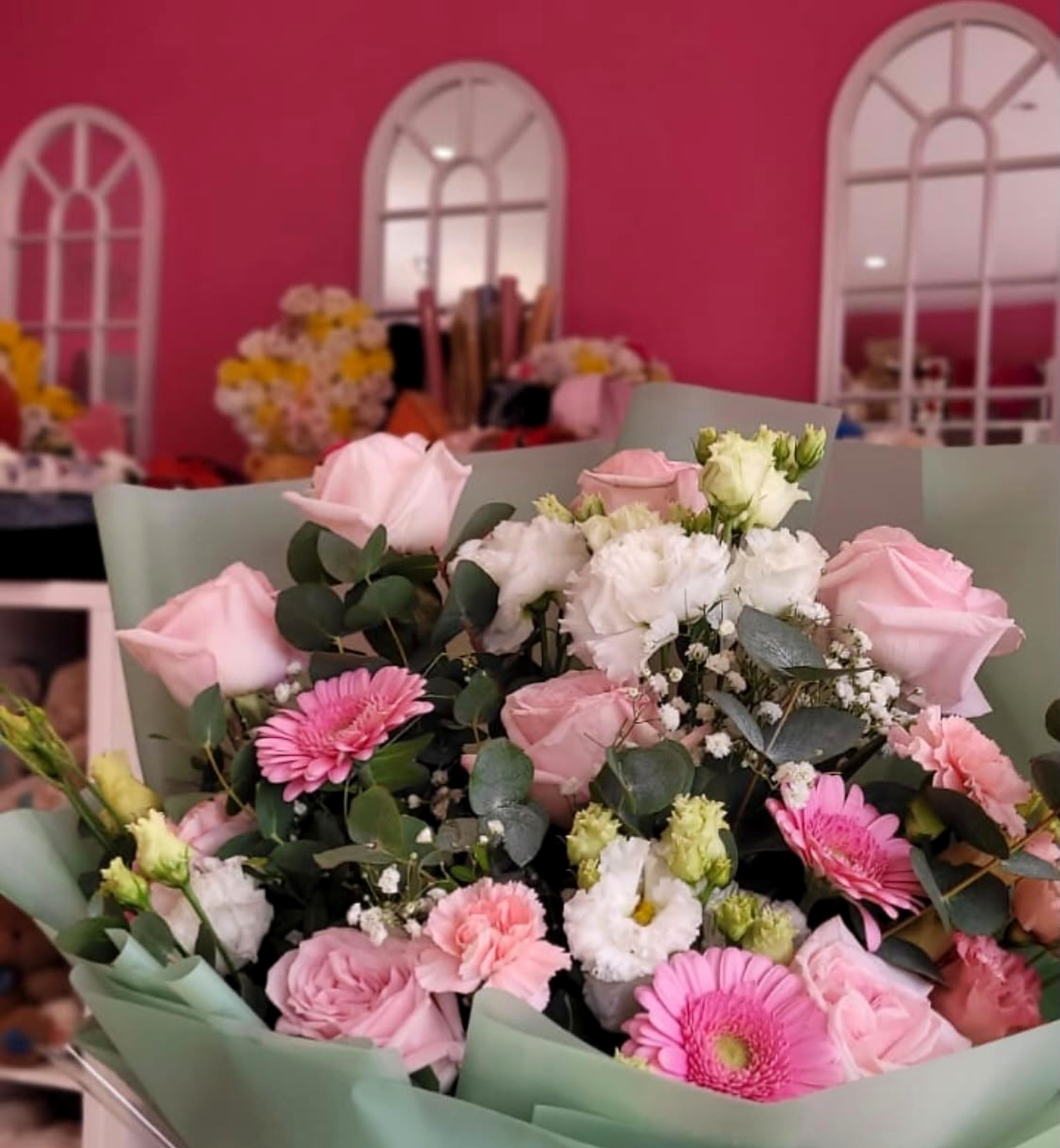 A hand-tied bouquet of pink and white roses, gerberas, and eucalyptus in the Wembley studio